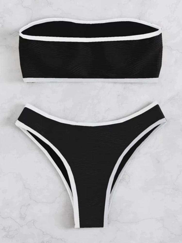Conjunto de biquíni preto com textura ondulada, viés preto e estilo fio dental, fotografado em fundo de mármore branco