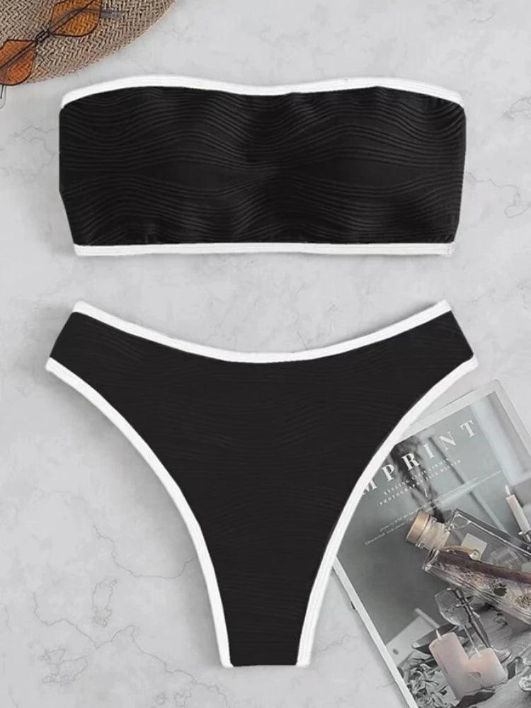 Biquíni preto texturizado com viés branco contrastante, modelo tomara-que-caia, fotografado em fundo de mármore