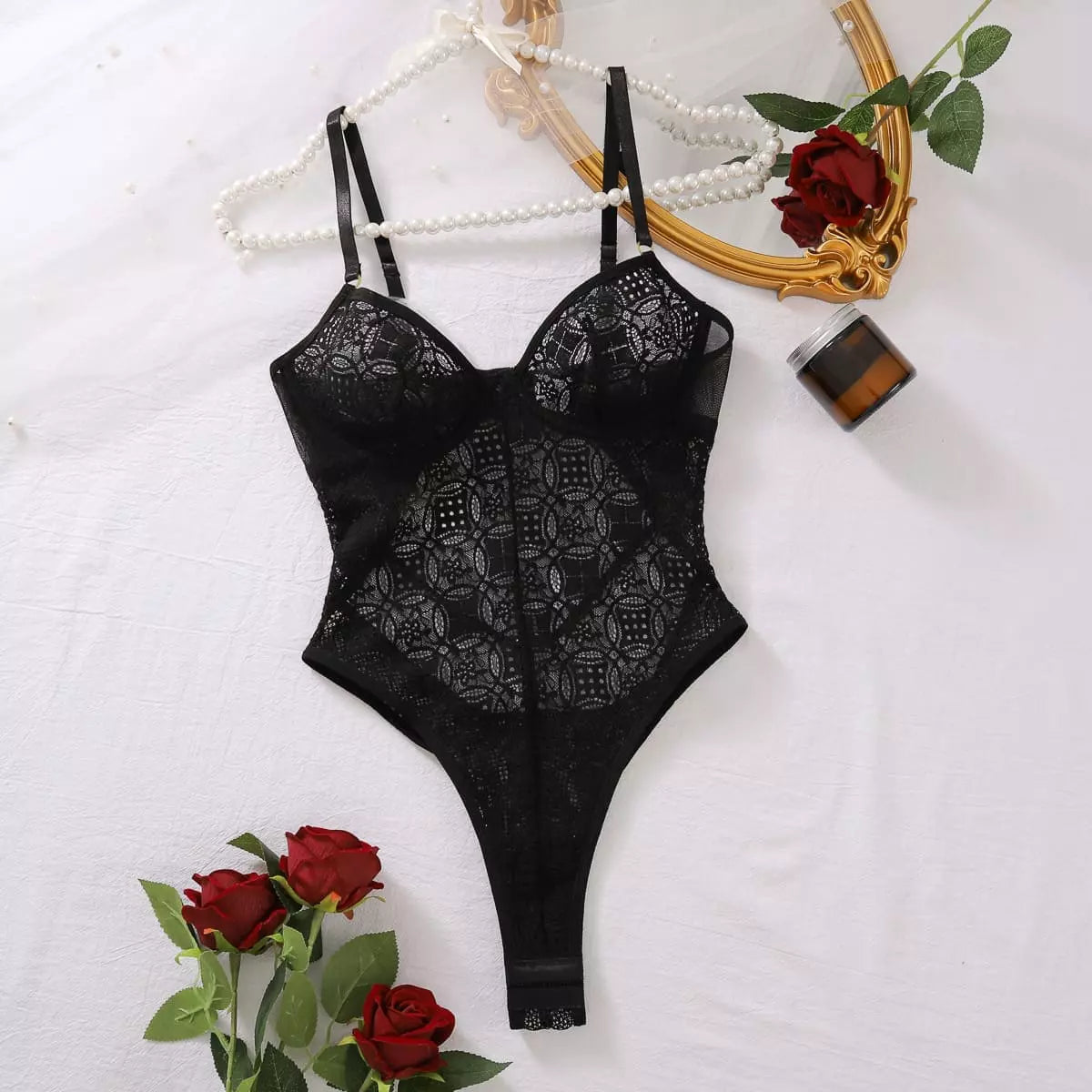 Body de renda premium preto em flat lay, decorado com rosas vermelhas e pérolas, visual romântico e elegante.