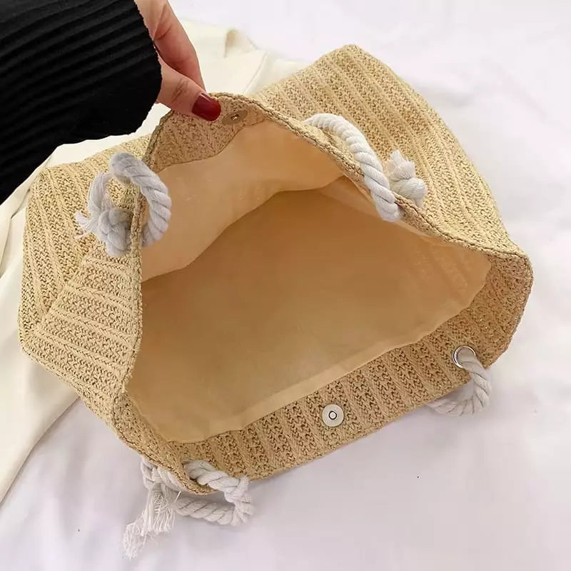 Bolsa de praia bege em palha trançada aberta mostrando interior espaçoso e forro bege