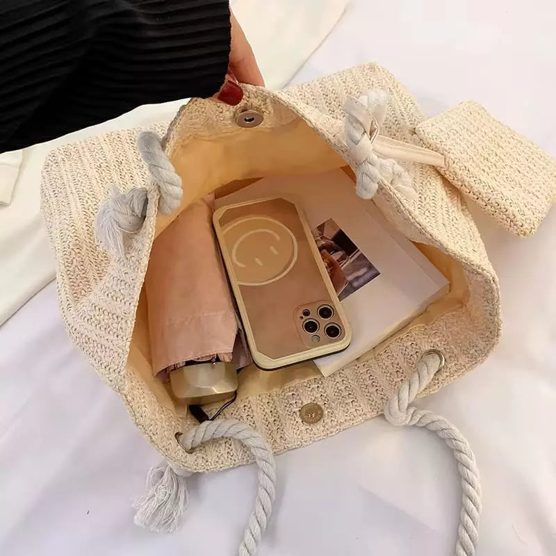 Bolsa de praia palha bege aberta com celular, óculos e acessórios, interior espaçoso