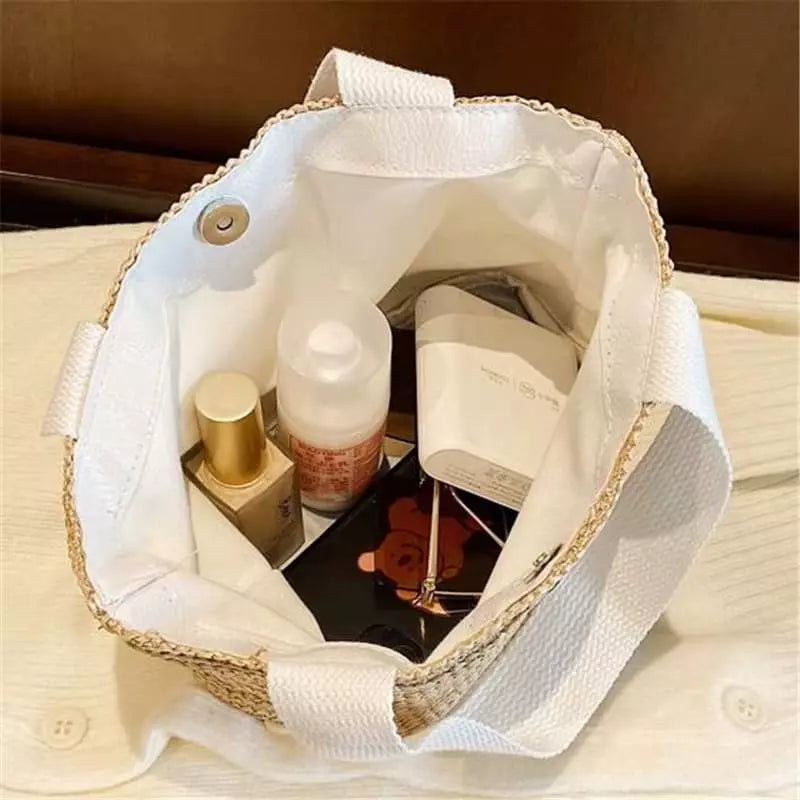 Bolsa de palha aberta mostrando compartimento interno com cosméticos e produtos de beleza