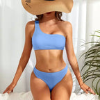 Biquíni azul canelado um ombro só com chapéu de palha, look fresco e elegante para praia.