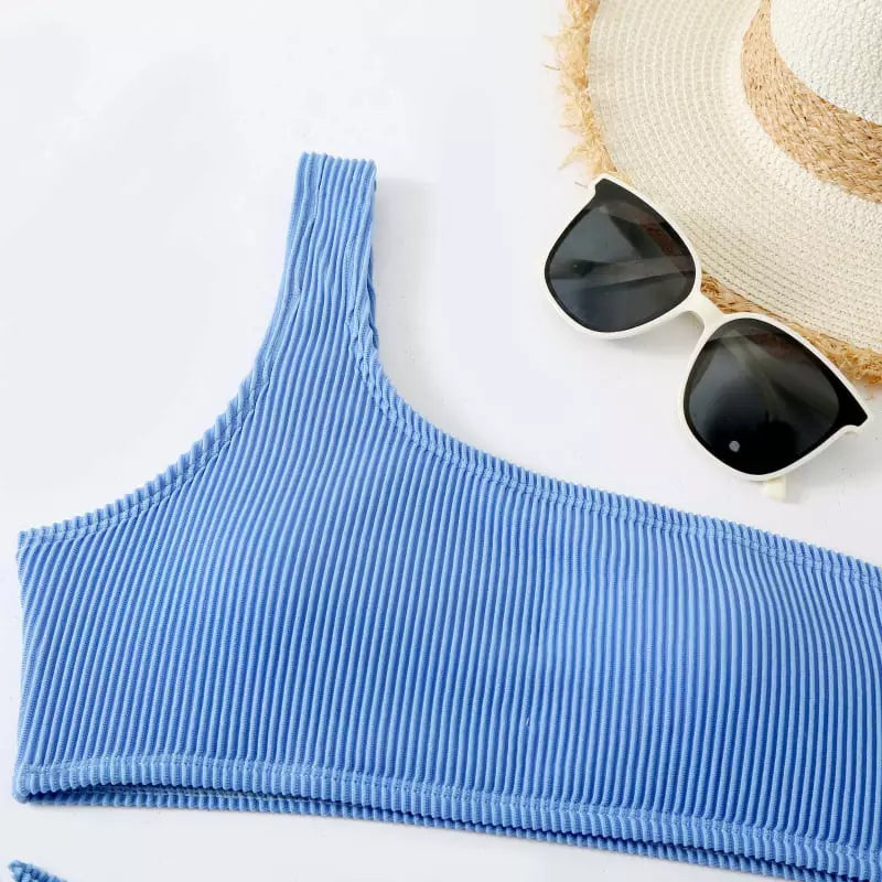 Top biquíni azul canelado com óculos escuros e chapéu de palha, conjunto praia verão.