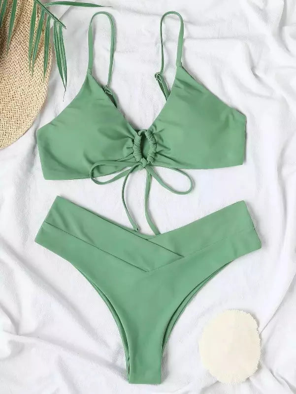 Biquíni verde menta com top de amarração frontal e calcinha cintura alta, fotografado em fundo branco com chapéu de palha.