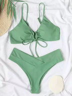 Biquíni verde menta com top de amarração frontal e calcinha cintura alta, fotografado em fundo branco com chapéu de palha.