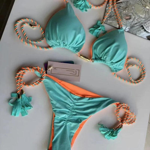 Biquini em tons de verde e laranja com detalhes decorativos em cordas trançadas. Inclui uma etiqueta de preço, sugerindo que se trata de um produto à venda.