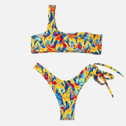 Biquíni estampado tropical em amarelo, azul e vermelho, modelo um ombro só e calcinha cavada com amarração lateral.