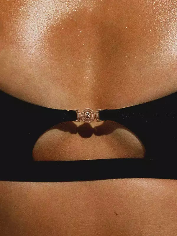 Detalhe biquíni preto com fivela dourada decorativa no centro do busto