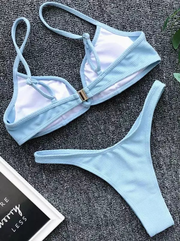 Biquíni azul claro texturizado, top triângulo com fecho dourado e calcinha cavada, tecido canelado.