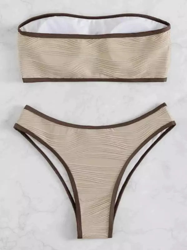 Conjunto de biquíni bege com textura ondulada, viés marrom e estilo fio dental, fotografado em fundo de mármore branco