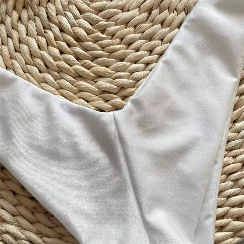 Calcinha de biquíni branca fio dental sobre base de palha natural trançada