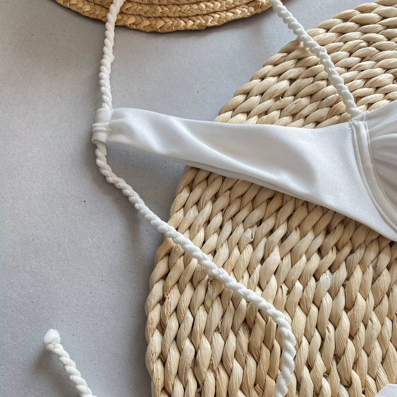 Top de biquíni branco com alças trançadas sobre base de palha natural trançada
