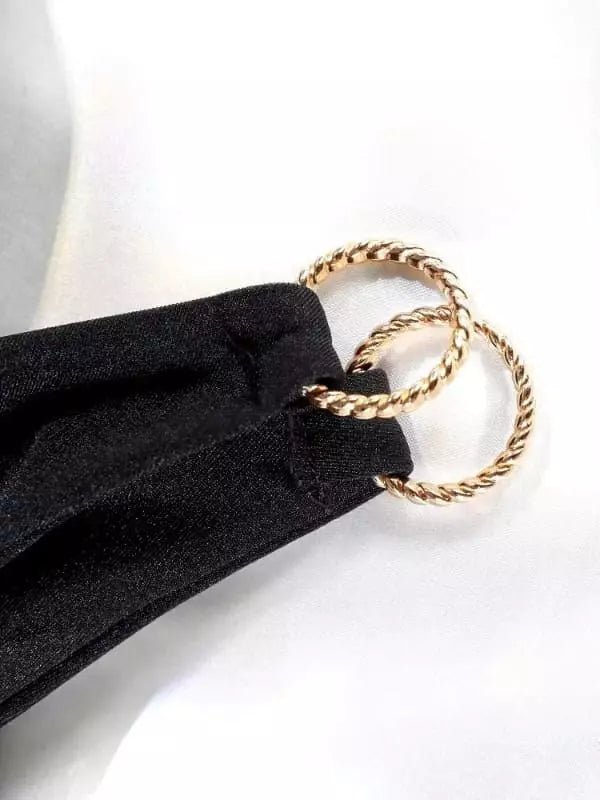 Detalhe de biquíni preto com argolas douradas trançadas