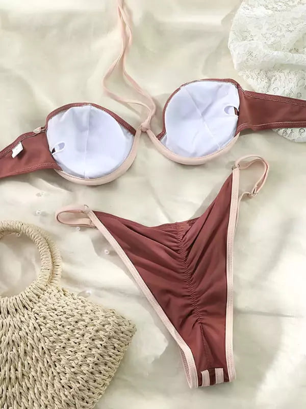 Biquíni marrom com bojo e detalhes bege, com bolsa de palha em fundo claro