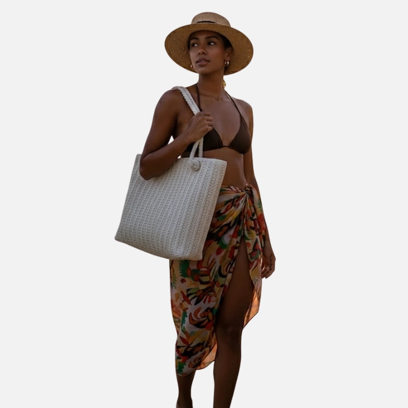 Mulher com bolsa de praia de palha grande caminhando ao pôr do sol em praia tropical