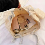 Bolsa de praia palha bege aberta com celular, óculos e acessórios, interior espaçoso