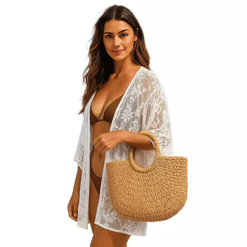 Mulher usando biquíni marrom com saída de praia branca rendada e bolsa de palha dourada