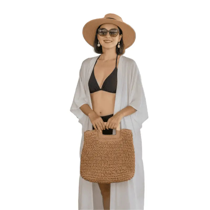 Mulher com biquíni preto, kimono branco, chapéu e bolsa de palha - look praia verão