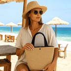 Mulher na praia com chapéu de palha, óculos escuros e bolsa bege, look resort verão