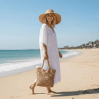 Vestido branco longo de praia com chapéu de palha e bolsa de crochê para look de verão tropical