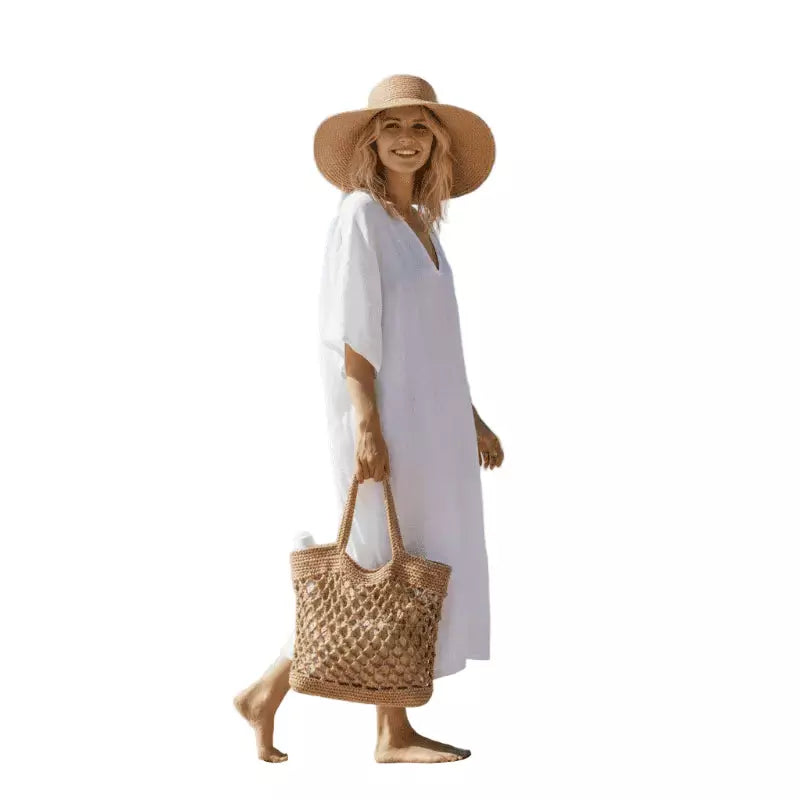 Mulher vestindo vestido branco longo com chapéu de palha e bolsa de crochê para look de verão
