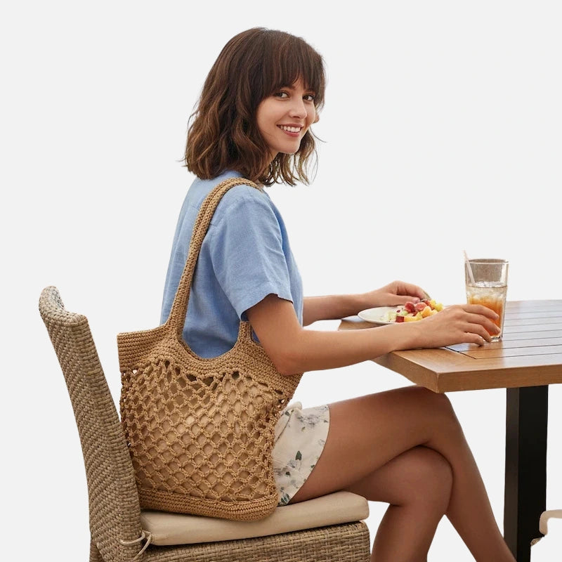 Bolsa de crochê grande bege com trama vazada estilo praia em ambiente litorâneo
