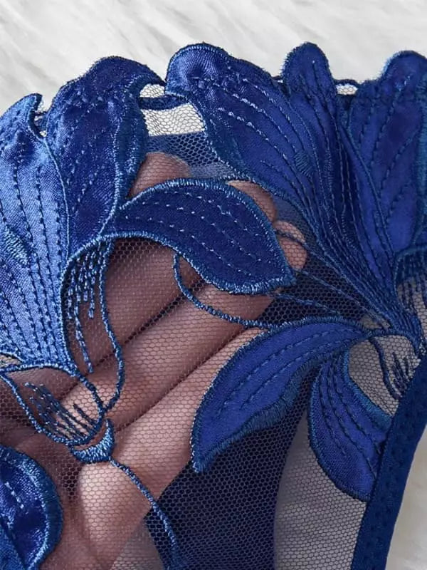 Detalhe de renda floral azul marinho sobre tela transparente em lingerie delicada