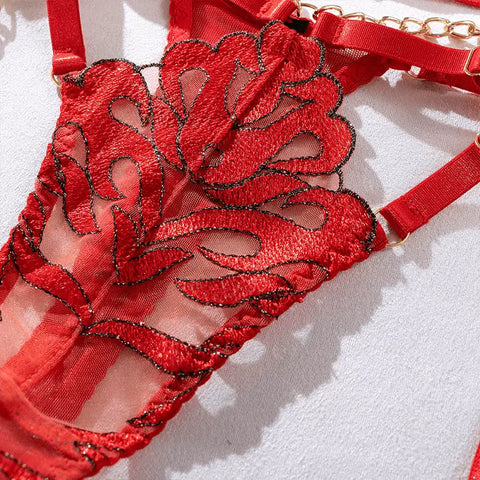 Lingerie vermelha decorativa com padrões de renda intrincados e detalhes de correntes douradas.