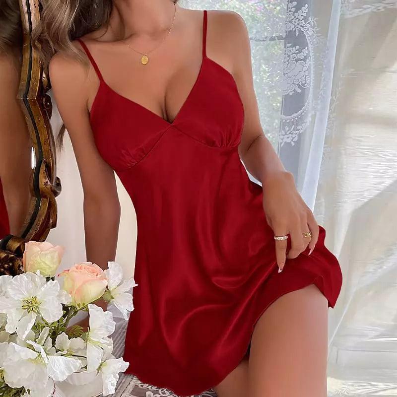 Camisola vermelho intenso em cetim com alças finas e decote V, em ambiente iluminado com flores brancas.