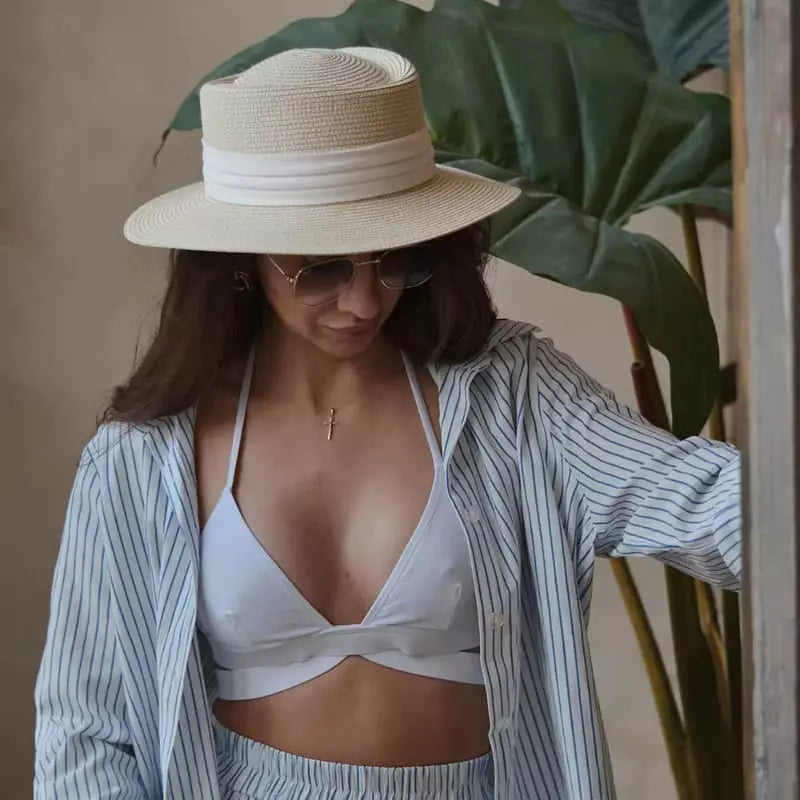 Chapéu de palha branco com faixa, óculos escuros e camisa listrada azul em look praia verão