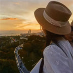 Chapéu de palha marrom com faixa branca ao pôr do sol look casual feminino