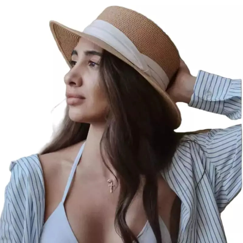 Mulher jovem usando chapéu de palha bege, blusa listrada azul e colar dourado em look casual