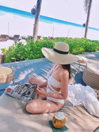 Chapéu de palha bege com fita preta, aba larga flexível ideal para relaxar na praia