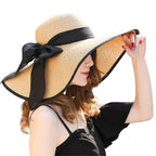 Uma mulher usando um elegante chapéu de palha bege com fita preta, perfeito para proteção solar