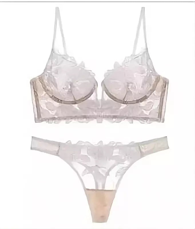 Conjunto de lingerie branca com renda floral transparente, sutiã meia taça e calcinha fio dental com acabamento ondulado.