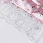 Detalhe de lingerie delicada com renda floral branca e tecido acetinado rosa, acabamento refinado para peças íntimas femininas.