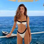 Biquíni branco com detalhes pretos, modelo em iate no mar azul, moda praia verão