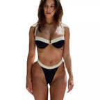 Mulher usando biquíni preto e branco com detalhes contrastantes, pose elegante em fundo claro
