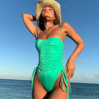 Mulher com maiô verde cavado franzido e amarração lateral na praia com chapéu de palha verão