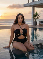 Maiô preto com recortes e tiras cruzadas em área de piscina ao entardecer