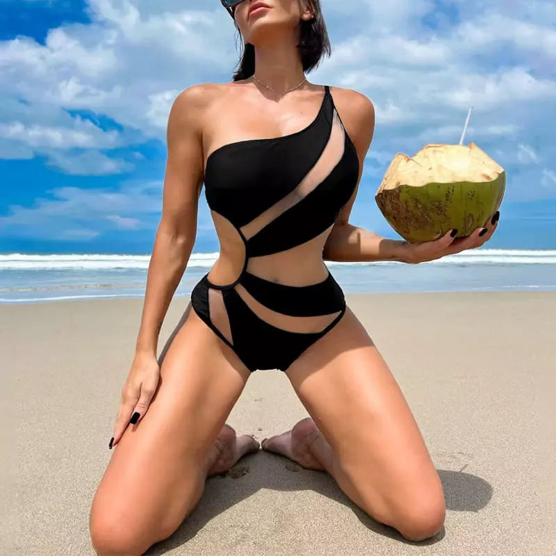 Biquíni preto assimétrico com recortes, mulher com coco na praia, moda praia tropical e estilosa.
