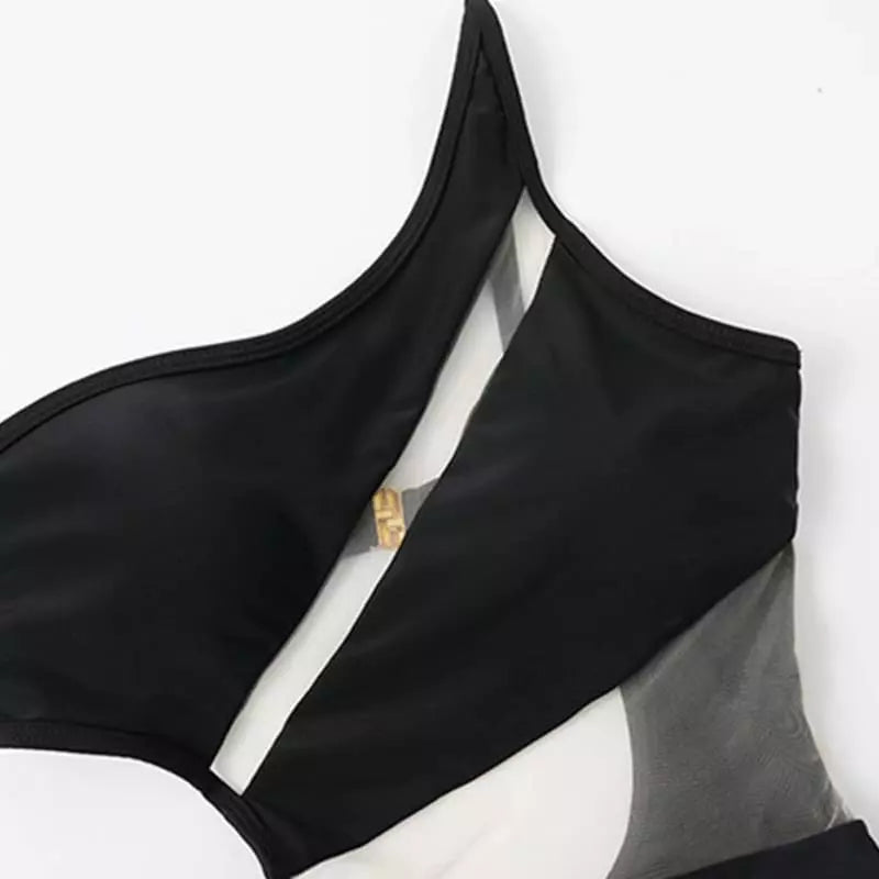 Maiô preto com recorte transparente e detalhe dourado, fundo branco, moda praia elegante e moderna.