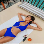 Maiô azul royal com detalhes em argolas douradas, recortes modernos na barriga, estilo monoquíni para praia e piscina.