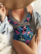 Maiô floral em azul e rosa com alças douradas trançadas, chapéu de palha e camisa jeans.