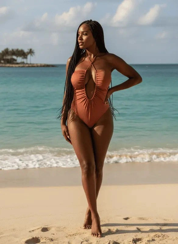 Maiô coral com decote central e franzidos, modelo na praia tropical com mar azul turquesa ao fundo