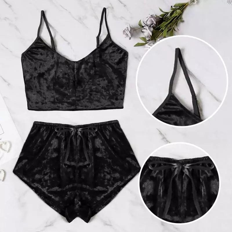 Conjunto de veludo preto com top cropped e shorts, com detalhes ampliados do acabamento e caimento. Fundo de mármore.