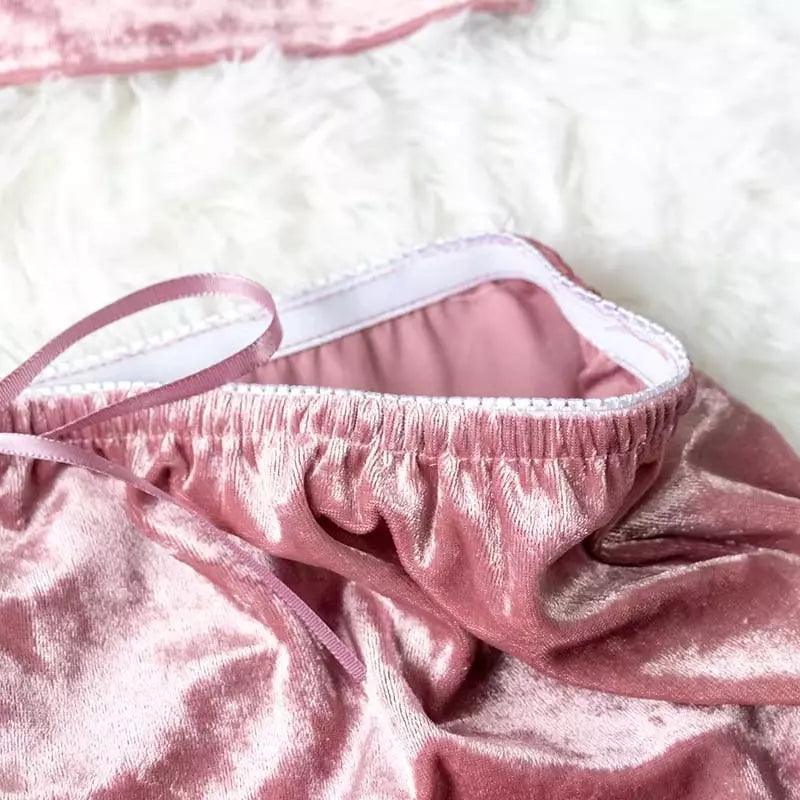 Detalhe do acabamento interno de shorts de veludo rosa, mostrando elástico e costura com fita de cetim. Tecido macio e brilhante.