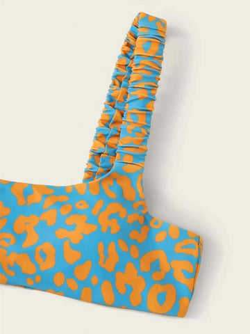 biquíni estampado com um decote ousado e profundo. O design brilhante e inspirado nos trópicos apresenta uma estampa abstrata repetida de leopardo ou chita em tons de azul, laranja e branco