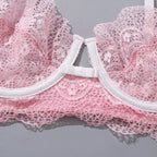 Detalhe do fecho e renda delicada de sutiã rosa claro com acabamento branco em elástico, textura floral em close.